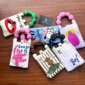 Collection of colorful children's bags with various designs on a wooden surface, featuring the brand 'Bela'.